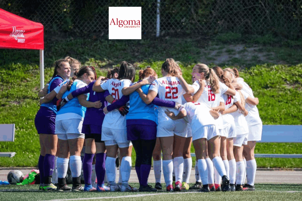 AlgomaU female soccer players huddled in circle