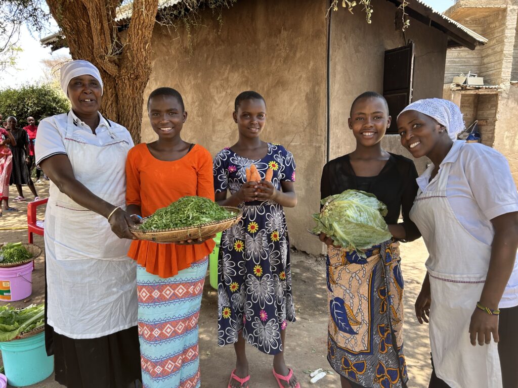 girls and women standing together holding vegetables