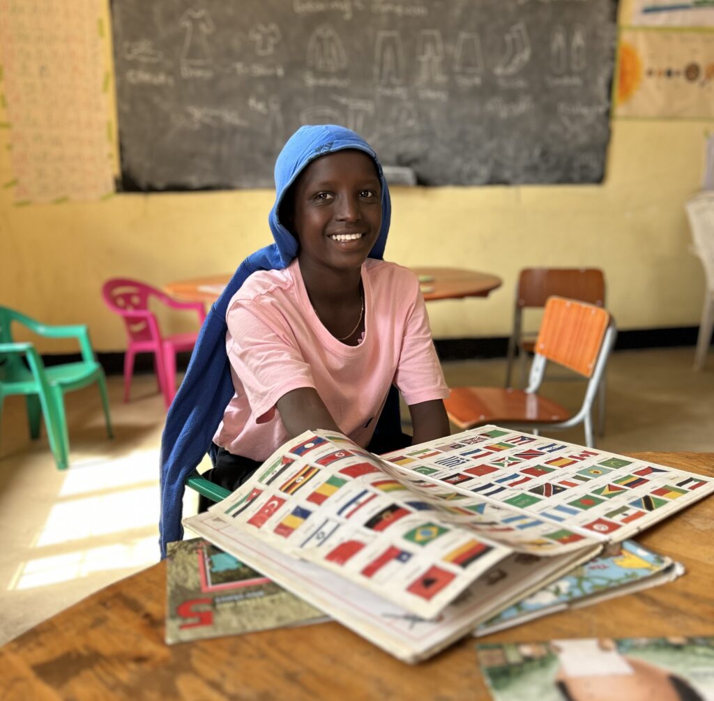 Senewa sitting at desk with book of flags in front of her